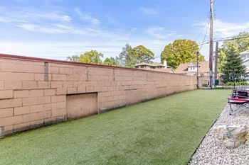 A backyard with a green lawn and a red brick wall.